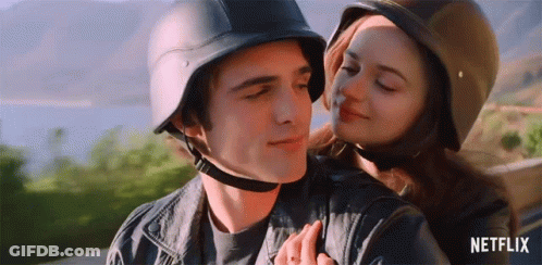 A Man And A Woman Wearing Helmets Are Hugging . GIF