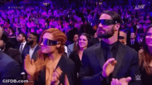A Man And A Woman Wearing Virtual Reality Glasses Are Sitting In A Crowd . GIF