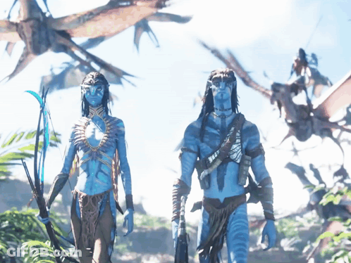 A Man And A Woman With Blue Faces Are Standing In A Field GIF
