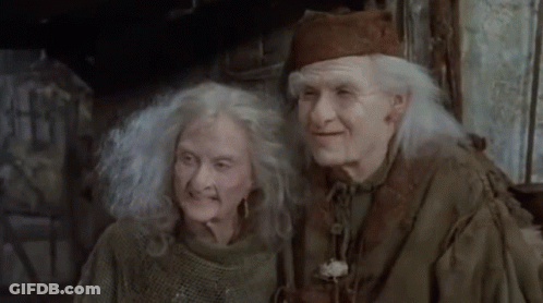 A Man And A Woman With Gray Hair Are Standing Next To Each Other And Smiling . GIF