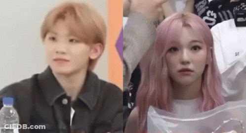 A Man And A Woman With Pink Hair Are Sitting Next To Each Other And Looking At The Camera . GIF