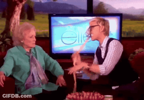 A Man And An Older Woman Are Sitting In Front Of A Television Screen With The Word Ellen On It GIF