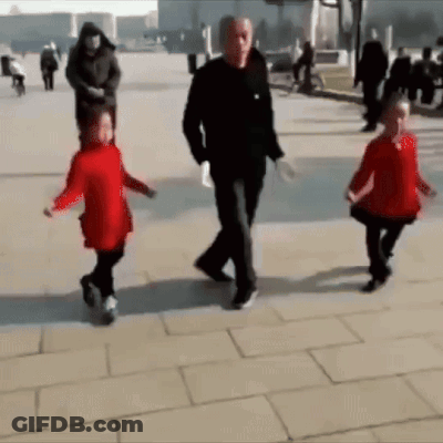 A Man And Two Children Are Walking Down A Sidewalk . GIF