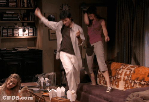 A Man And Two Women Are Jumping On A Couch GIF