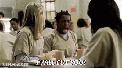 A Man And Two Women Are Sitting At A Table In A Jail Cell Talking To Each Other . GIF