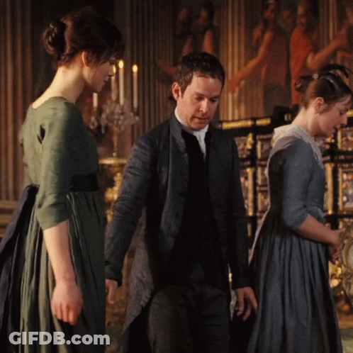 A Man And Two Women Are Standing In A Room With Candles In The Background GIF