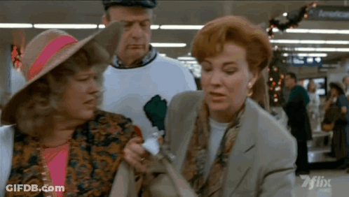 A Man And Two Women Are Standing In Front Of A Sign That Says American On It GIF