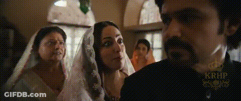 A Man And Two Women Are Standing Next To Each Other In A Room . One Of The Women Is Wearing A Veil . GIF