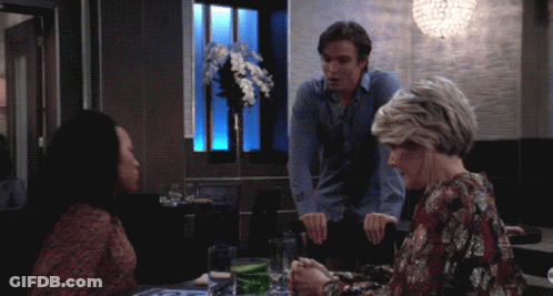 A Man And Two Women Sit At A Table In A Restaurant Talking GIF