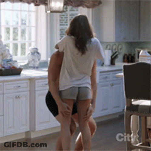 A Man And Woman Are Dancing In A Kitchen With A City Logo On The Bottom GIF