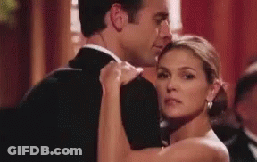 A Man And Woman Are Dancing Together In A Ballroom . GIF