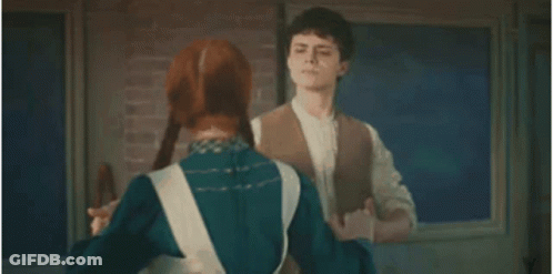 A Man And Woman Are Dancing Together In Front Of A Brick Wall . GIF