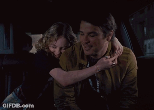 A Man And Woman Are Holding Hands In A Car GIF