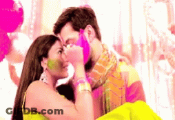 A Man And Woman Are Kissing And The Woman Is Covering The Man 'S Face With Holi Paint GIF