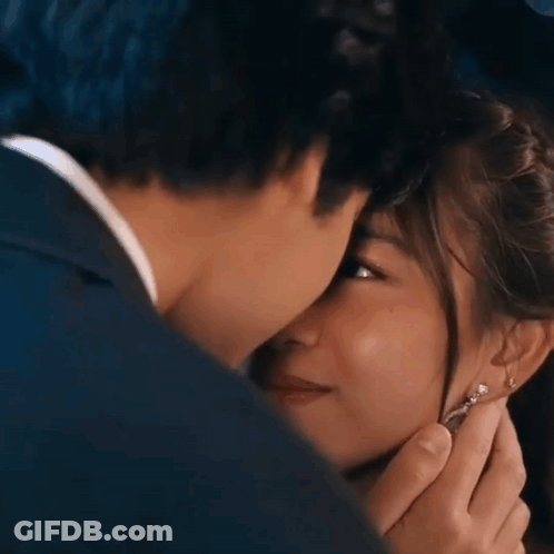A Man And Woman Are Kissing And The Woman Is Wearing Earrings . GIF