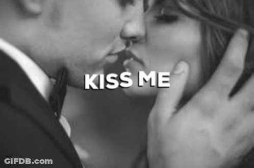 A Man And Woman Are Kissing In A Black And White Photo . GIF