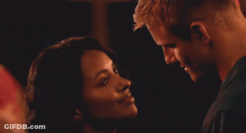 A Man And Woman Are Kissing In A Crowded Room GIF