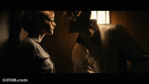 A Man And Woman Are Kissing In A Dark Room . GIF