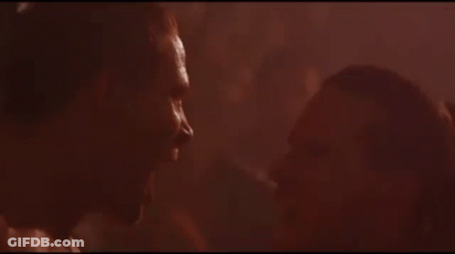 A Man And Woman Are Kissing In A Dark Room In A Movie . GIF