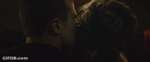 A Man And Woman Are Kissing In A Dark Room GIF