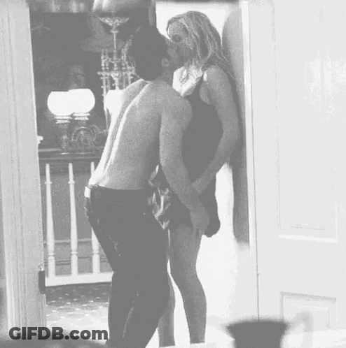 A Man And Woman Are Kissing In A Doorway . GIF