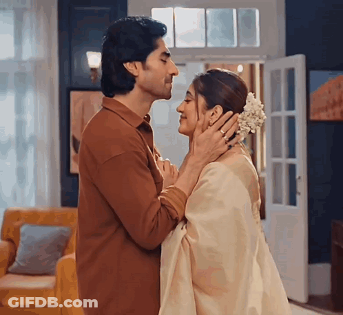 A Man And Woman Are Kissing In A Living Room GIF