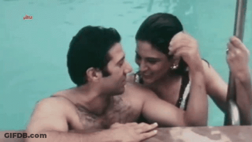 A Man And Woman Are Kissing In A Pool . GIF