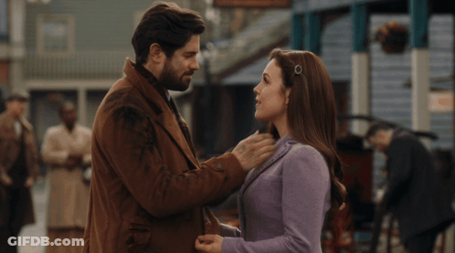 A Man And Woman Are Kissing In Front Of A Crowd Of People GIF