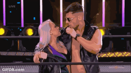 A Man And Woman Are Kissing In Front Of A Sign That Says Live On It GIF