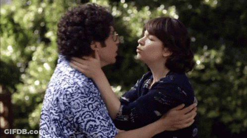 A Man And Woman Are Kissing In Front Of A Tree GIF
