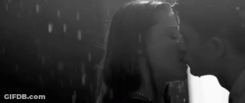 A Man And Woman Are Kissing In The Rain . GIF