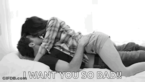A Man And Woman Are Kissing On A Bed . GIF