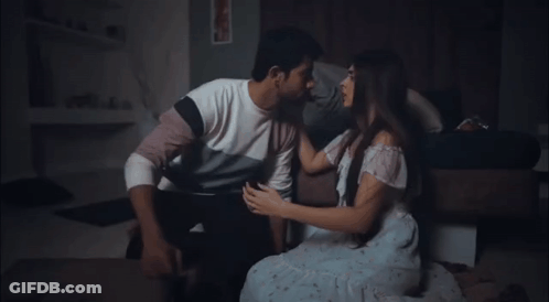 A Man And Woman Are Kissing On The Floor In A Dark Room . GIF