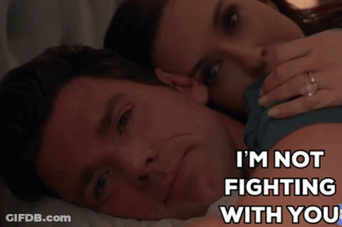 A Man And Woman Are Laying On A Bed With The Words I 'M Not Fighting With You GIF