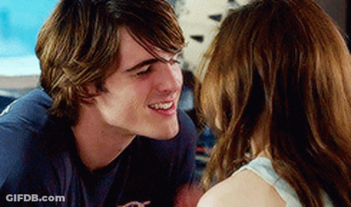 A Man And Woman Are Looking At Each Other And Smiling . GIF