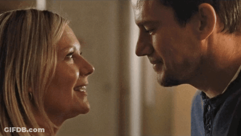 A Man And Woman Are Looking At Each Other And Smiling GIF