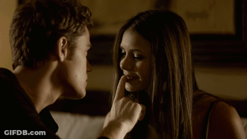 A Man And Woman Are Looking At Each Other And The Woman Is Holding Her Finger To Her Lips GIF