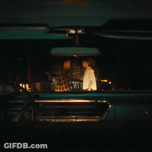 A Man And Woman Are Looking At Each Other In A Car GIF