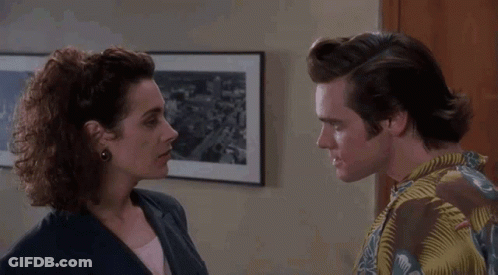 A Man And Woman Are Looking At Each Other In Front Of A Framed Picture GIF