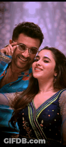 A Man And Woman Are Posing For A Picture And The Woman Is Wearing Sunglasses GIF