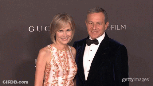 A Man And Woman Are Posing For A Picture In Front Of A Wall That Says Gucci Film GIF