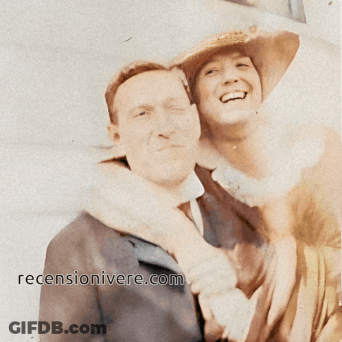 A Man And Woman Are Posing For A Picture With The Website ' Recensionivere.com ' On The Bottom Right GIF