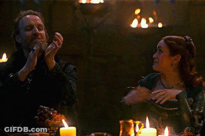 A Man And Woman Are Sitting At A Table With Candles GIF