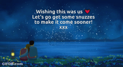 A Man And Woman Are Sitting In Front Of A Body Of Water With A Wishing Message GIF