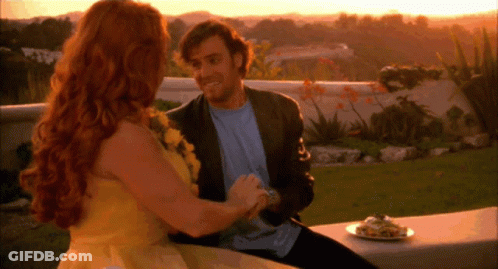 A Man And Woman Are Sitting On A Bench With A Plate Of Food In Front Of Them GIF
