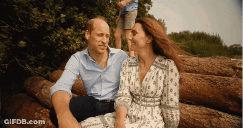 A Man And Woman Are Sitting On A Pile Of Logs GIF