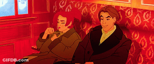 A Man And Woman Are Sitting On A Red Couch GIF