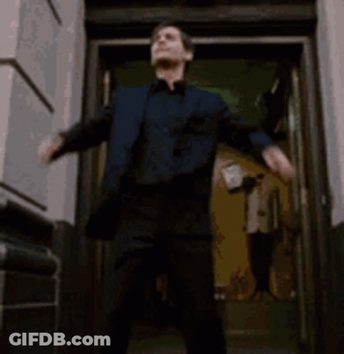 A Man And Woman Are Standing In A Doorway . GIF