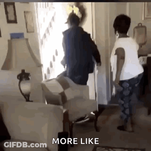 A Man And Woman Are Standing In A Living Room With The Words More Like Below Them . GIF