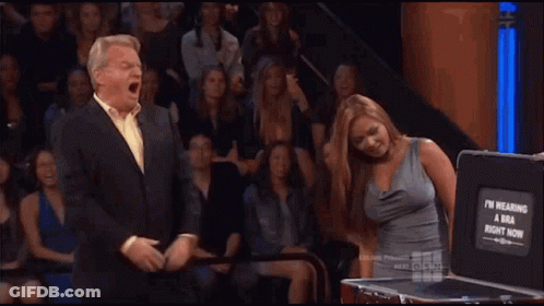 A Man And Woman Are Standing In Front Of A Briefcase That Says I 'M Wearing A Bra GIF